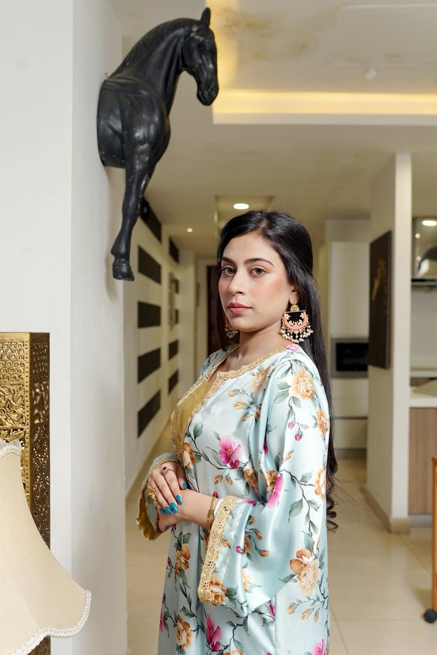 Woman in a floral dress standing in an indoor setting with decorative elements.